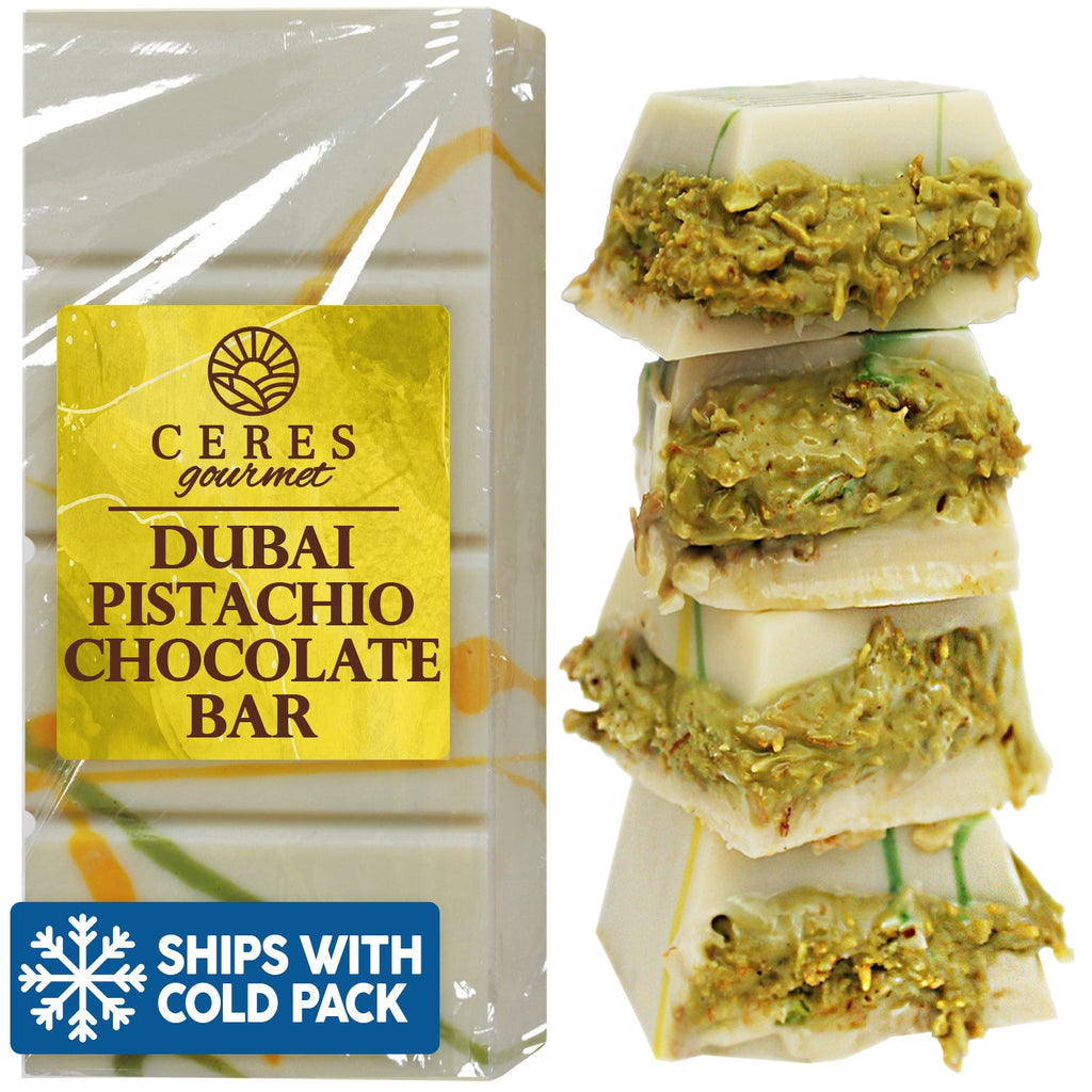 On the left is a packaged Ceres Gourmet Dubai Chocolate Kunafa Pistachio (Dark, White, Milky, 3.5 oz); on the right, four pieces show white chocolate with crushed pistachios. A Ships With Cold Pack icon is at bottom left.