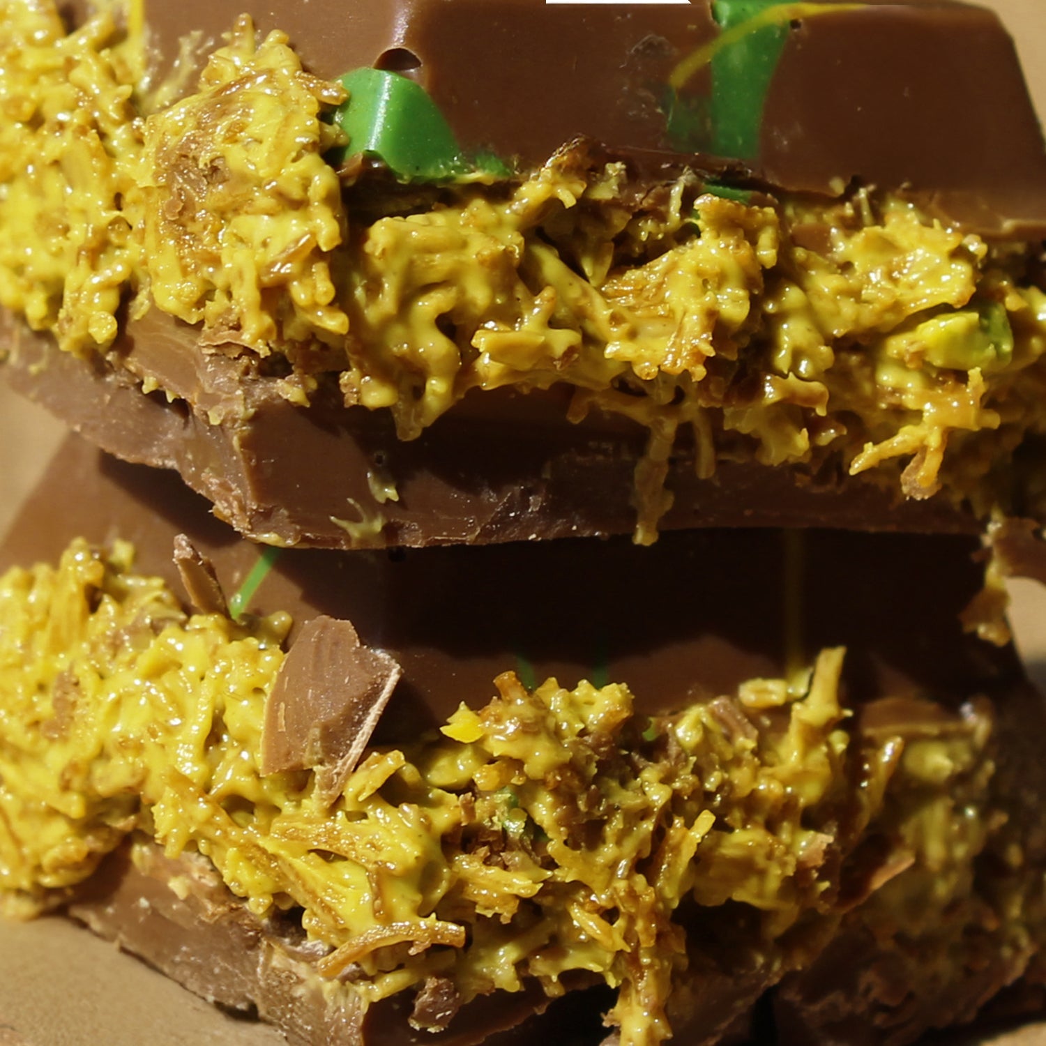 Close-up of two stacked Ceres Gourmet Dubai Chocolate Bar Pistachio with Milky Chocolate and Knafeh, featuring a textured, yellow-green kunafa filling and green streaks atop the chocolate. 3.5 oz - Popular on TikTok.