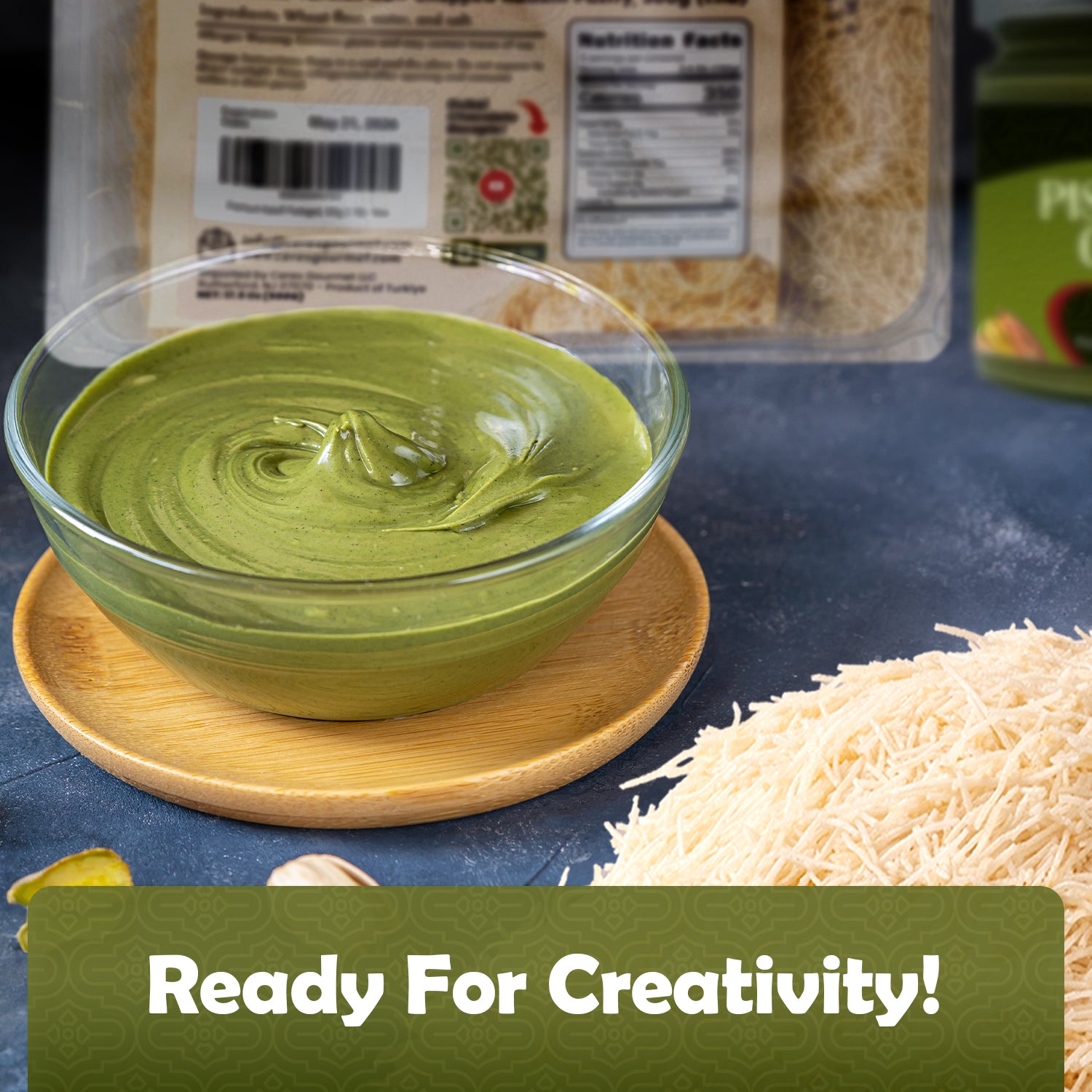 A bowl of creamy pistachio butter sits beside thin kataifi dough noodles on a wooden plate, with Ceres Gourmet Premium Kataifi & Pistachio Butter Bundle for Dubai Chocolate packaging in the background. Text: Ready For Creativity!.